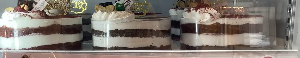 Deretan cake tart berlapis krim di dalam etalase Gege Bakery