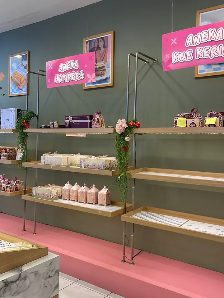 Rak berisi kemasan hampers di bawah papan Aneka Hampers